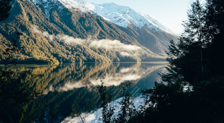 Mountainous landscape with a lake and reflection, surrounded by native New Zealand bush.